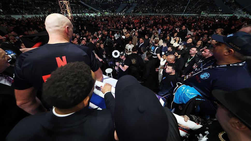 Tyson Fury speaks to a disinterested Anthony Joshua at ringside