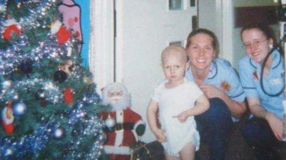 Louis as a child in hospital with two smiling nurses