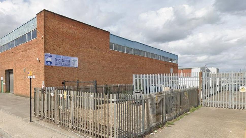 A Google Street View of a large rectangular brick building behind metal railings.