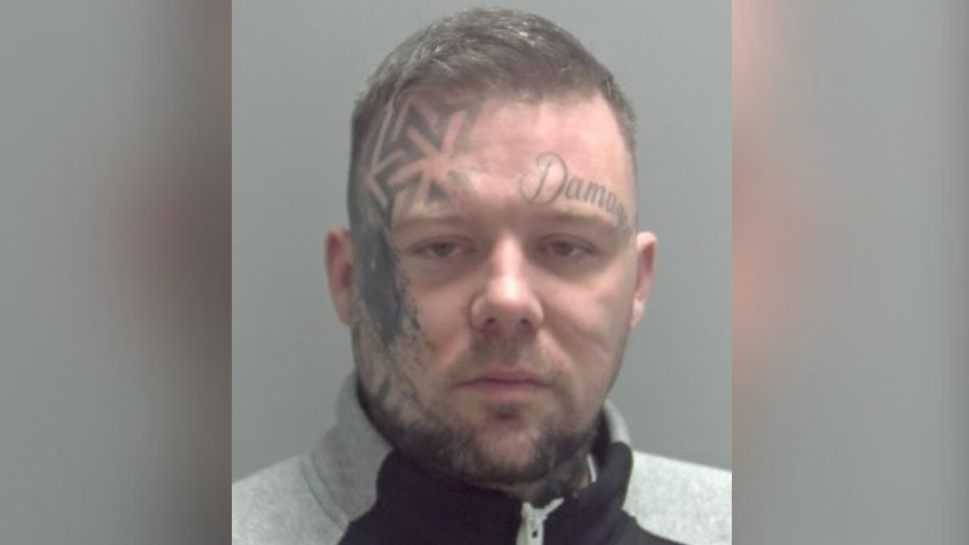 Daryl Taylor posing for his police mugshot. He is a white man with tattoos on his face - including one which reads 'Damaged'.