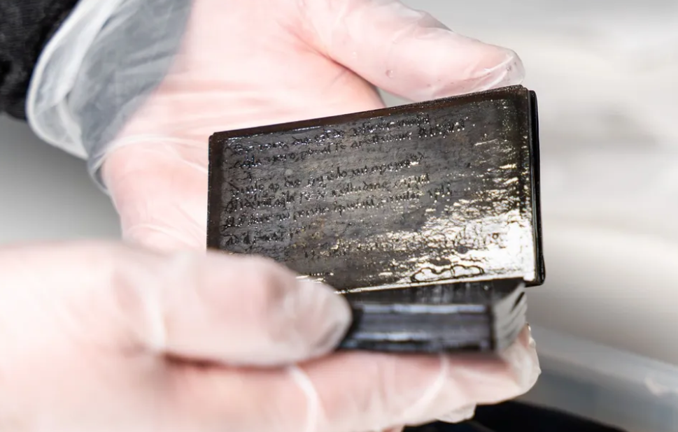 A conservator holds the wood and wax booklet