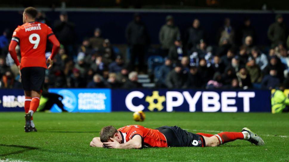 Mark McGuinness lies with his head in his hands during Luton Town's defeat by Queens Park Rangers