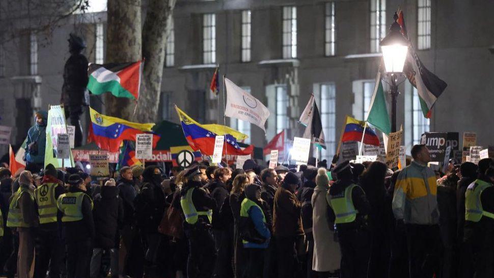 Oficerët e policisë bëjnë roje ndërsa demonstruesit mbajnë pankarta dhe flamuj gjatë një proteste në Londër kundër sulmeve të SHBA-së kundër Venezuelës dhe kapjes së Presidentit Venezuelian Nicolas Maduro nga trupat amerikane.