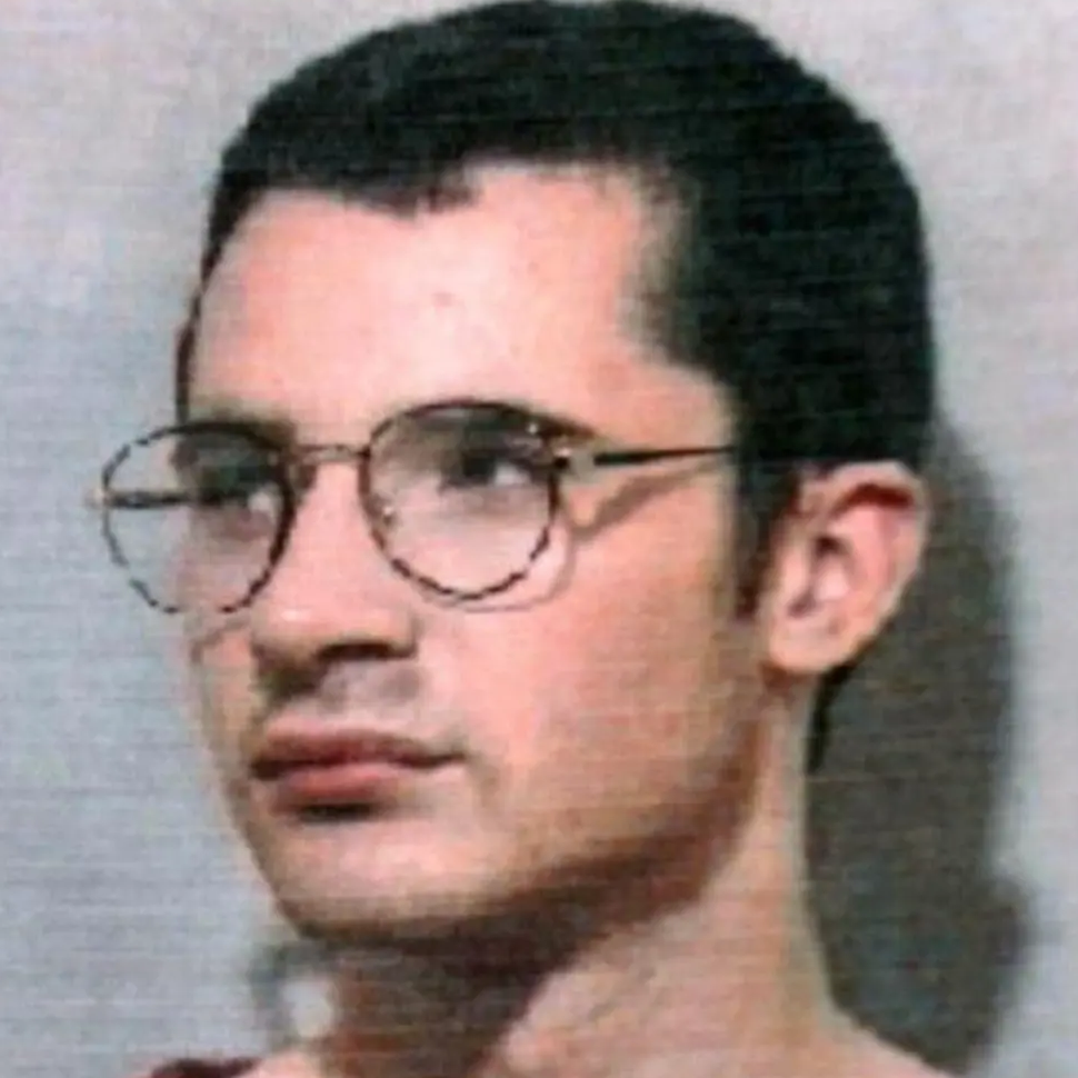 A mugshot of McKilligan who has short, dark hair and large round glasses.