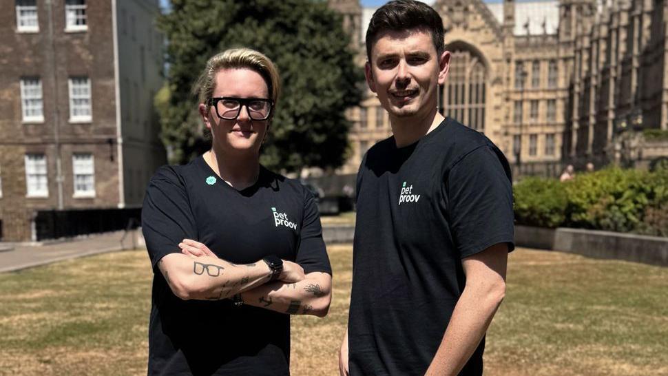 Kate Margolis with a business partner standing outside the Houses of Parliament on a sunny day. They are both wearing black T-shirts with the words 'Pet proov' on them in white writing.