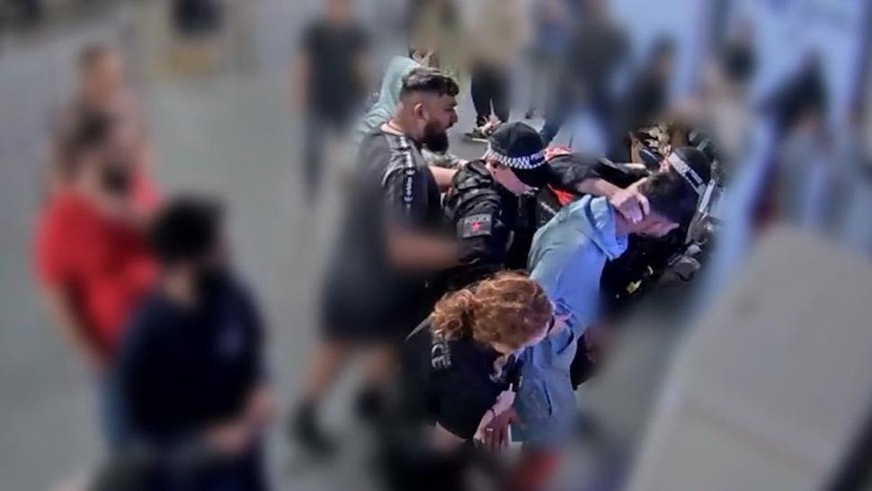 A video grab image issued by the Crown Prosecution Service 
from CCTV footage at Manchester Airport which has been played to jurors at Liverpool Crown Court. Three officers are standing around Mohammed Fahir Amaaz while his brother is standing behind them. One of the officers as his hand on the back of Amaaz's neck. 