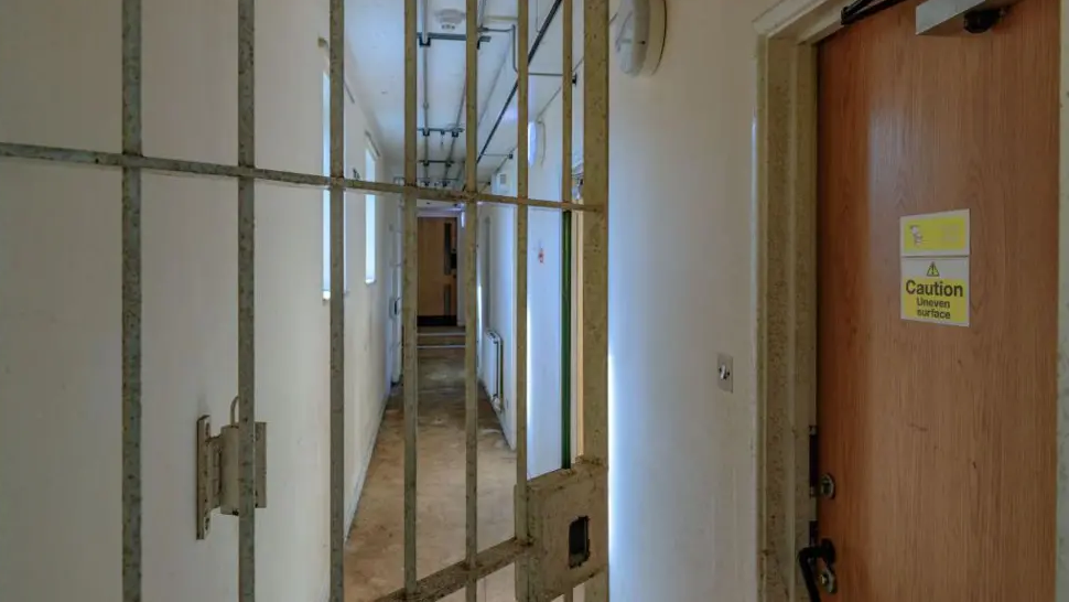 An open gate and a door with a sign saying "caution: uneven surface" at Campsfield House.