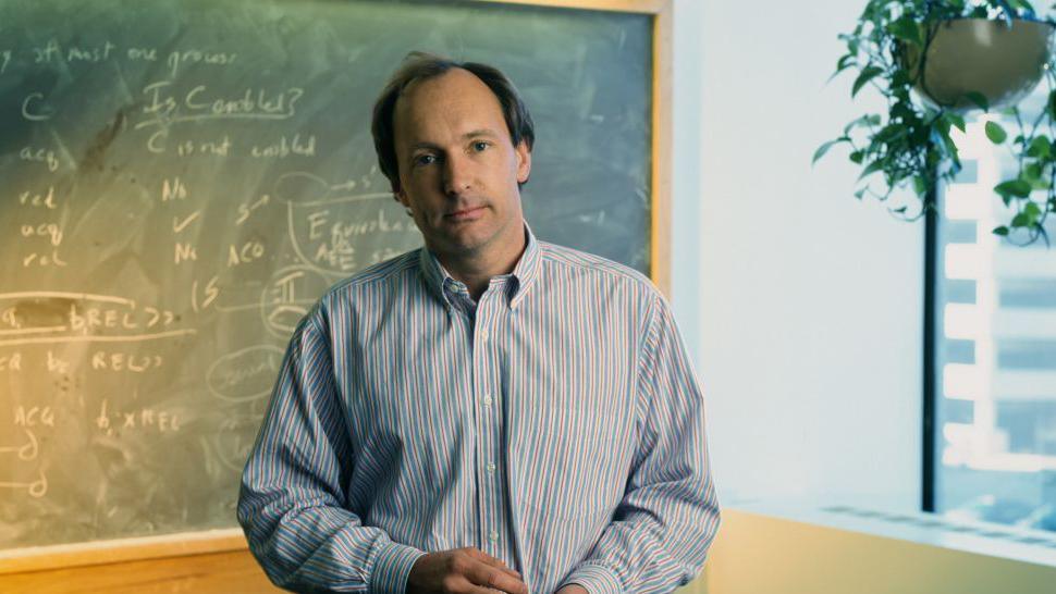 Tim Berners-Lee standing in front of a black board.