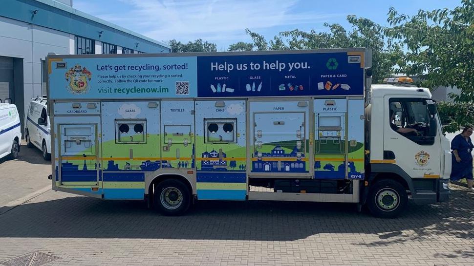 A large waste collection truck with doors and compartments for cardboard, glass, textiles, cans, paper, and plastic.