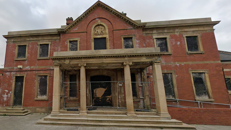A dilapidated frontage of an abandoned swimming baths.