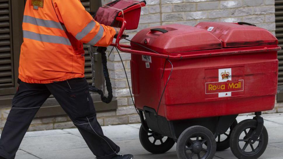 A post man wheeling a trolley full of letters.