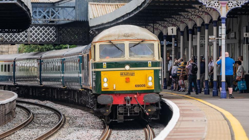 A diesel locomotive and carriages at a railway station