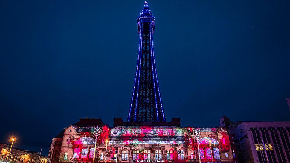 Blackpool Tower lit up blue at night with a projection artwork on the Tower building.