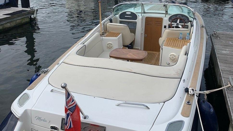 A blue and white boat moored up to a pontoon with a union flag at the back