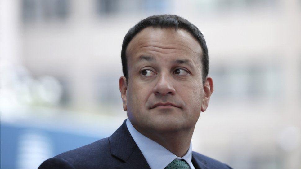 Former taoiseach  (Irish prime minister) Leo Varadkar looks over his shoulder to the right. he is wearing a dark blue suit, light blue shirt and green tie