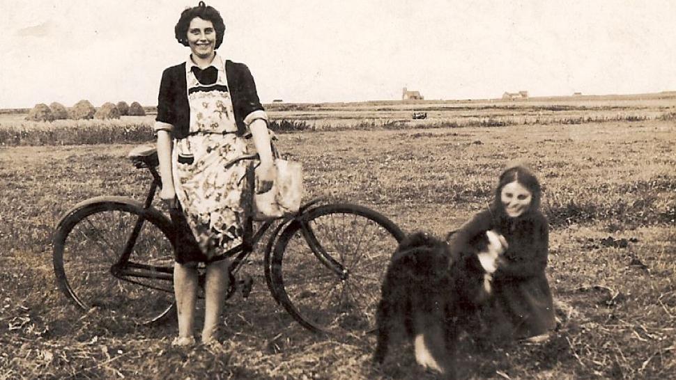 A woman with a bike and a girl on the ground with a dog