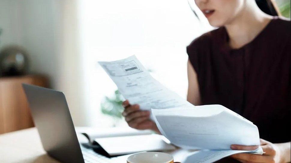 Woman sitting at laptop looking at bills