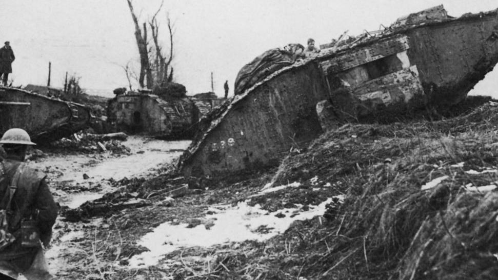 A tank in thick mud at Arras, France, is watched by British troops as it climbs over an embankment.