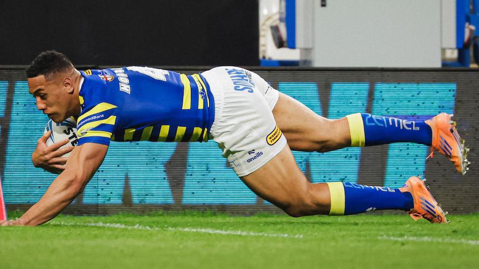 Warrington Wolves winger Albert Hopoate diving to score a try in the corner.