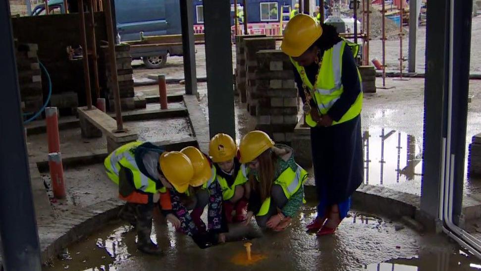 A number of school children in high-vis jackets and hard hats with mayor Lillian Seenoi-Barr