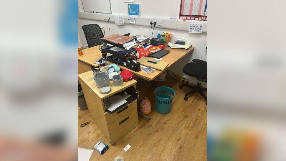 A smashed drawer and various items scattered on the laminate floor on Sunderland Mind in Hendon following one of the break-ins. The desk is covered in paper and there is a Union Jack flag across it.