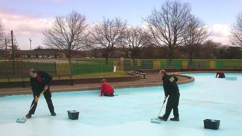 Men with rollers paint the pool
