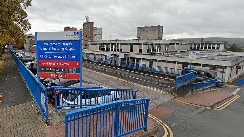 External view of the entrance and sign which reads 'Burnley General Teaching Hospital' showing vehicle parked outside the main building