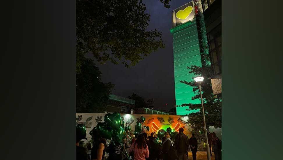 An image of the Grenfell Tower lit up in green against the backdrop of a night sky in London on Wednesday night, with people gathered at the base