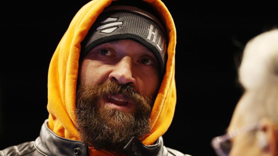 A bearded Tyson Fury in an orange hoodie