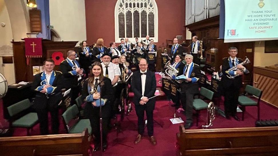 A number of people with various instruments at the front of a church.