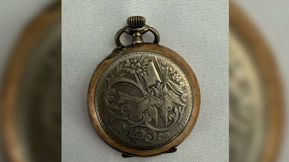 The decorated front of the pocket watch showing a leafy pattern