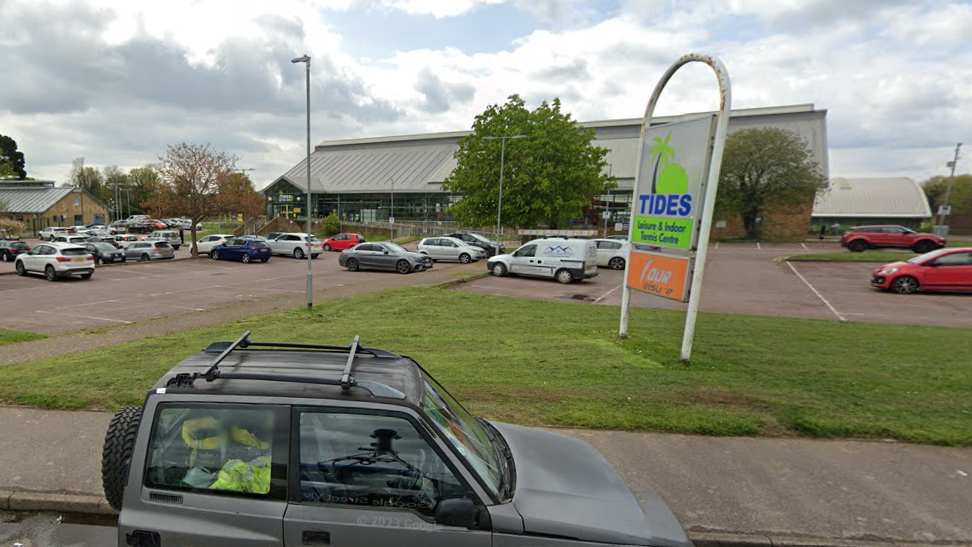 Tides Leisure Centre in Deal with a car park in front of the centre, and a green sign