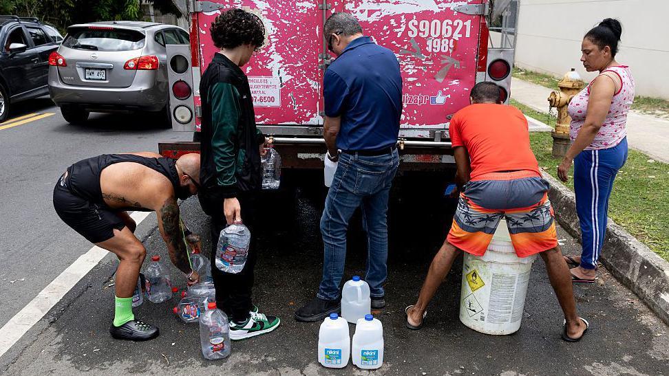A group of people filling up water containers at a truck
