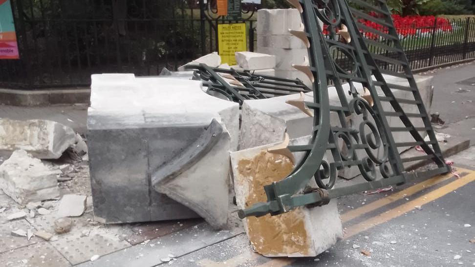 A close-up of the damage, with the gate partially off its hinges. Stone debris can be seen on the floor.