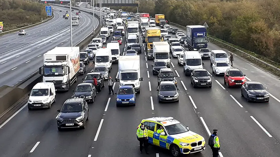 A police car blocks six lanes of traffic across the M25 