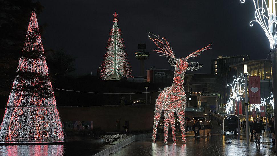 Giant illuminated Christmas trees and a reindeer at the Liverpool ONE shopping shown in the evening. 