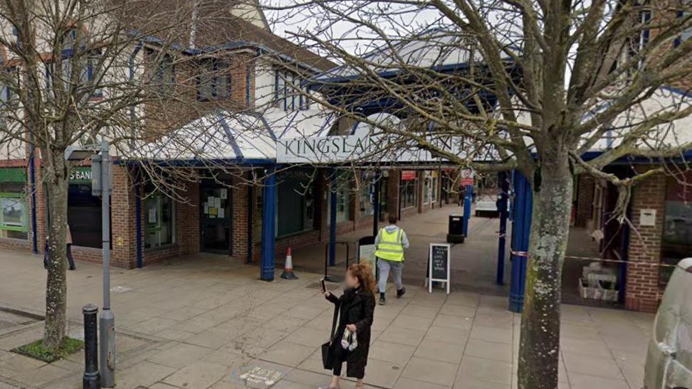 A google maps view of the front of the Kingsland Centre, a small shopping quadrangle in Thatcham. Trees partially obscure the sign at the front.