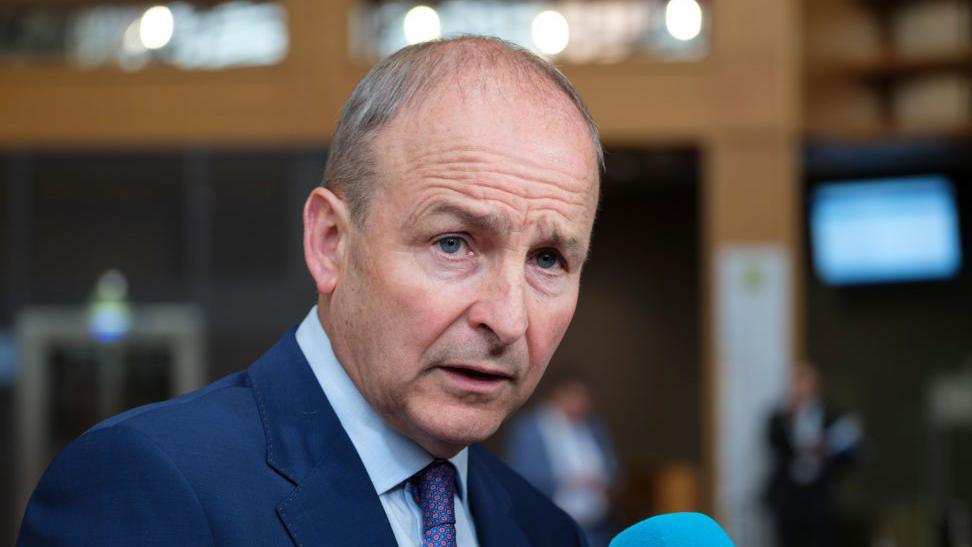 Micheal Martin wears a navy suit and blue shirt 