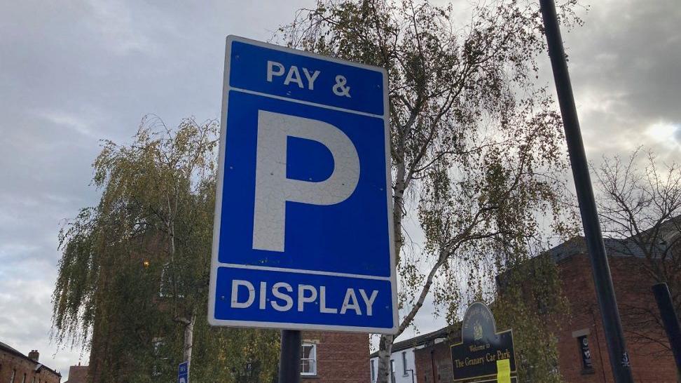 A pay and display blue parking sign in a car park