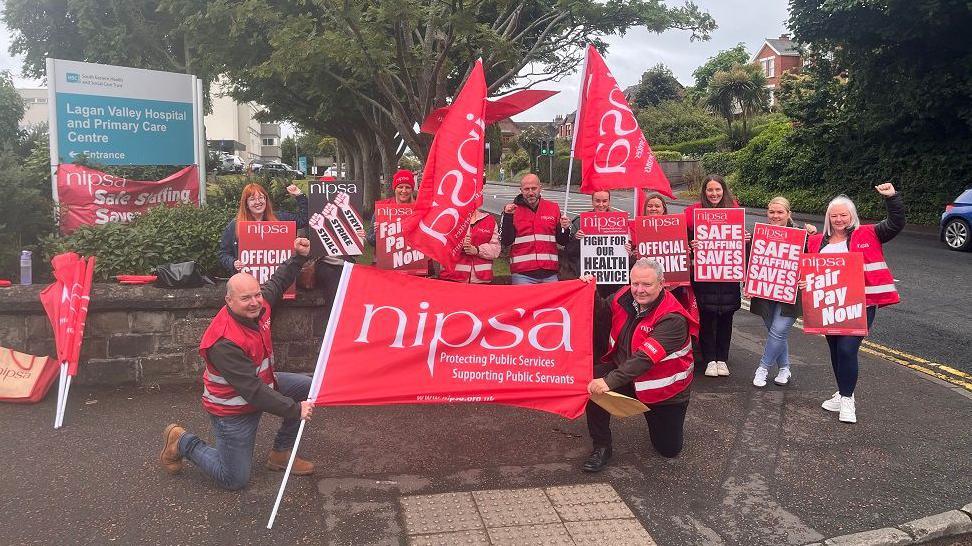 People outside with red flags that read NIPSA and signs 