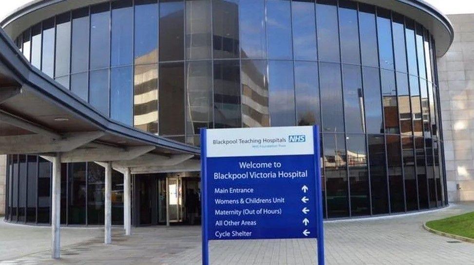 An outside view of Blackpool Victoria Hospital, and a sign with the hospital name printed on