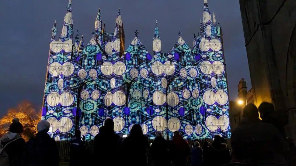 Colourful lighting is projected on an historic cathedral in the dark.