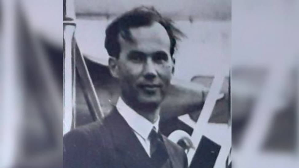 Black and white image of James Sayers. He is looking at the camera and wearing a suit.