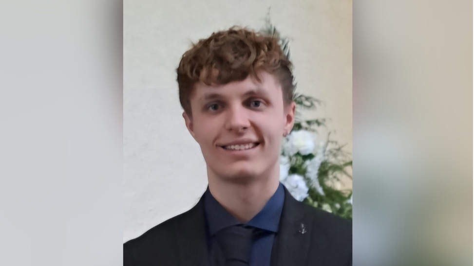 Kacper Dudek, a young man with short dark blond hair, wearing a dark suit and blue shirt 