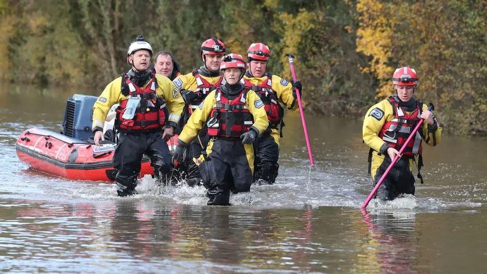 Emergency workers dressed in waders and hard hats tow a dinghy around flood water in Fishlake in 2019 