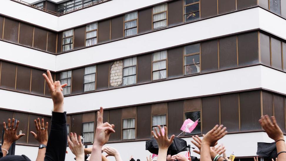 Anti Fascist protesters cheers and wave as men believed to be migrants gesture from a window of the Barbican Thistle Hotel as anti-immigration, 'stand up to racism' and 'anti-fascist' groups all gather outside on August 2, 2025 in London, England. 