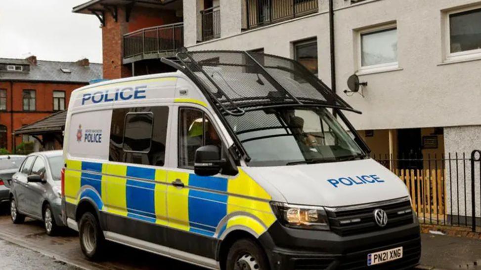 A Greater Manchester police van is parked outside flats in the Freehold area of Rochdale.