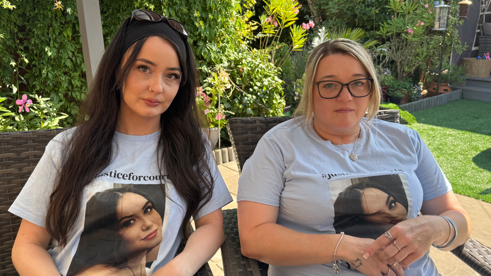 Charleigh and Samantha Mitchell sitting next to each other in two garden chairs in the garden. They are both wearing blue T-shirts with Courtney Mitchell's face on them. They are both looking into the camera.