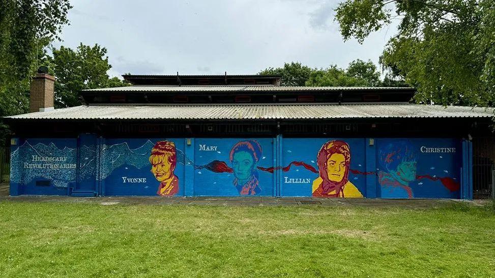 The mural on a blue background on the Maurice Rawlings Community Centre