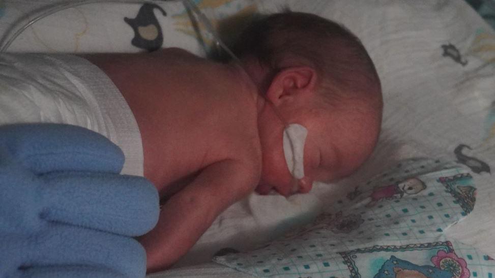 A premature baby sleeps next to a cotton bonding heart at Rotherham Hospital.